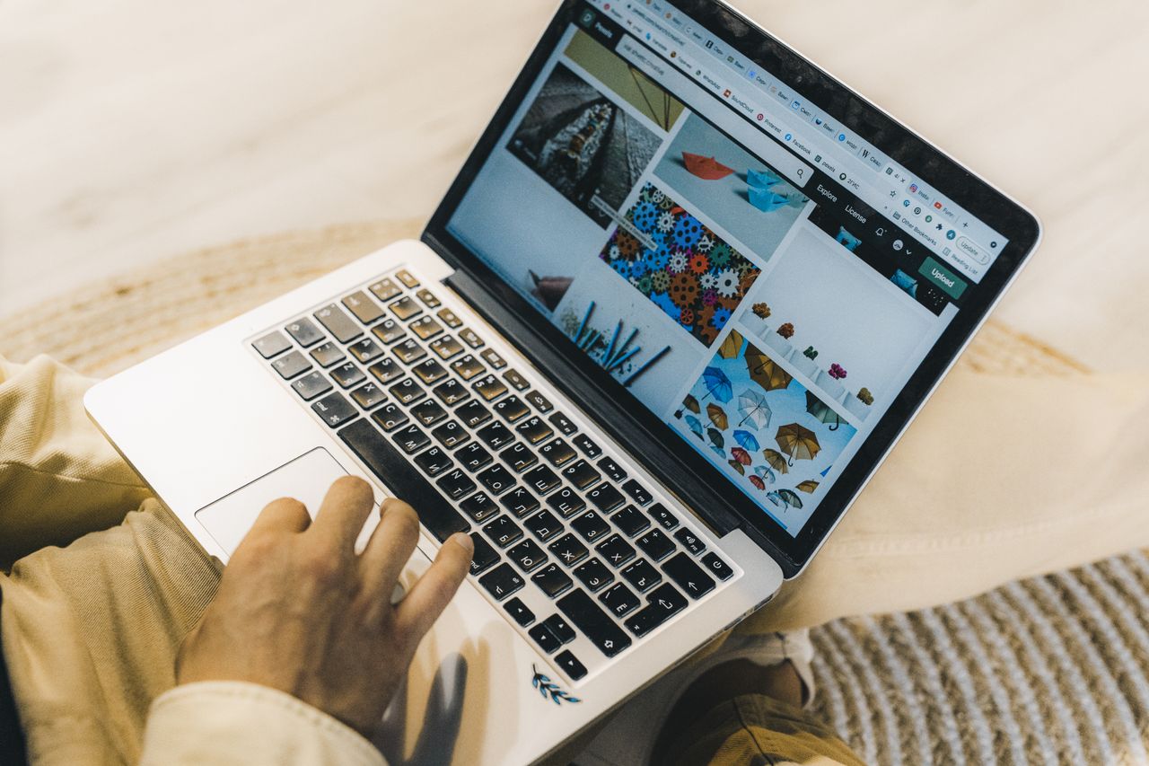 Una persona che usa un laptop per navigare siti di stock photo. Lavoro freelance in un ambiente accogliente.